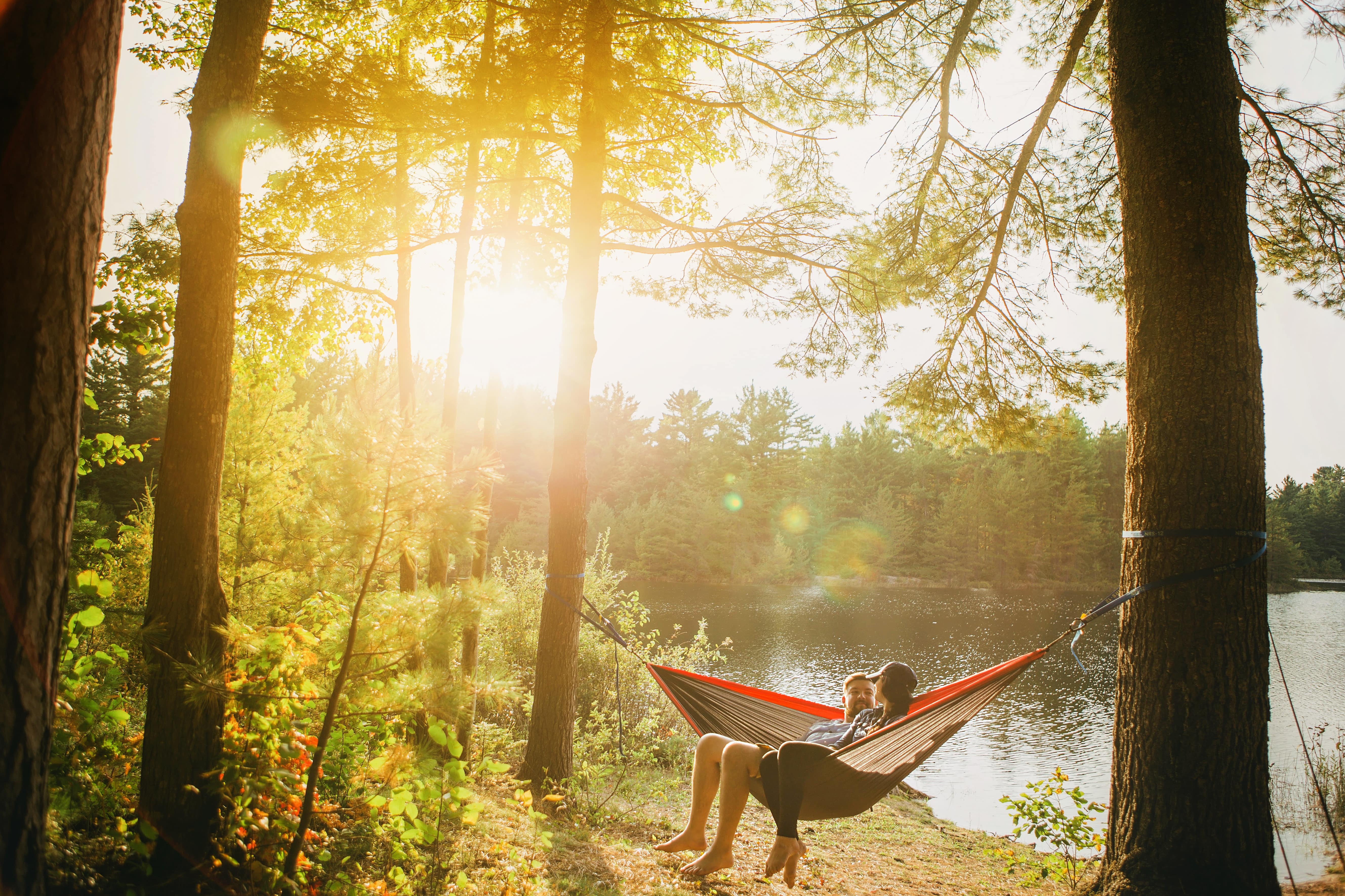 A couple relaxing by a lake in a hammock in the afternoon sun after simplifying their life