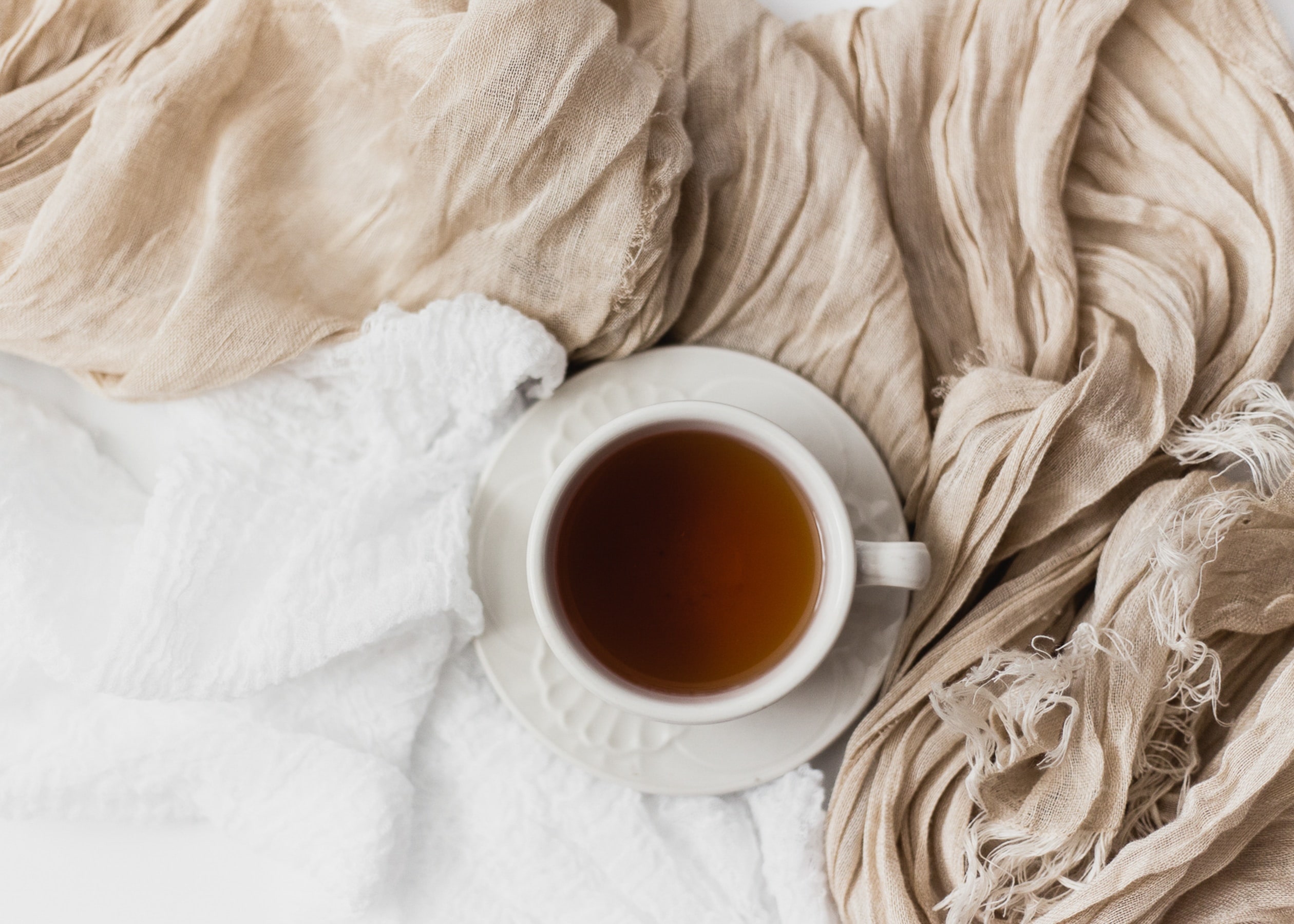 A coffee cup on a bed with sheets. A cosy space.