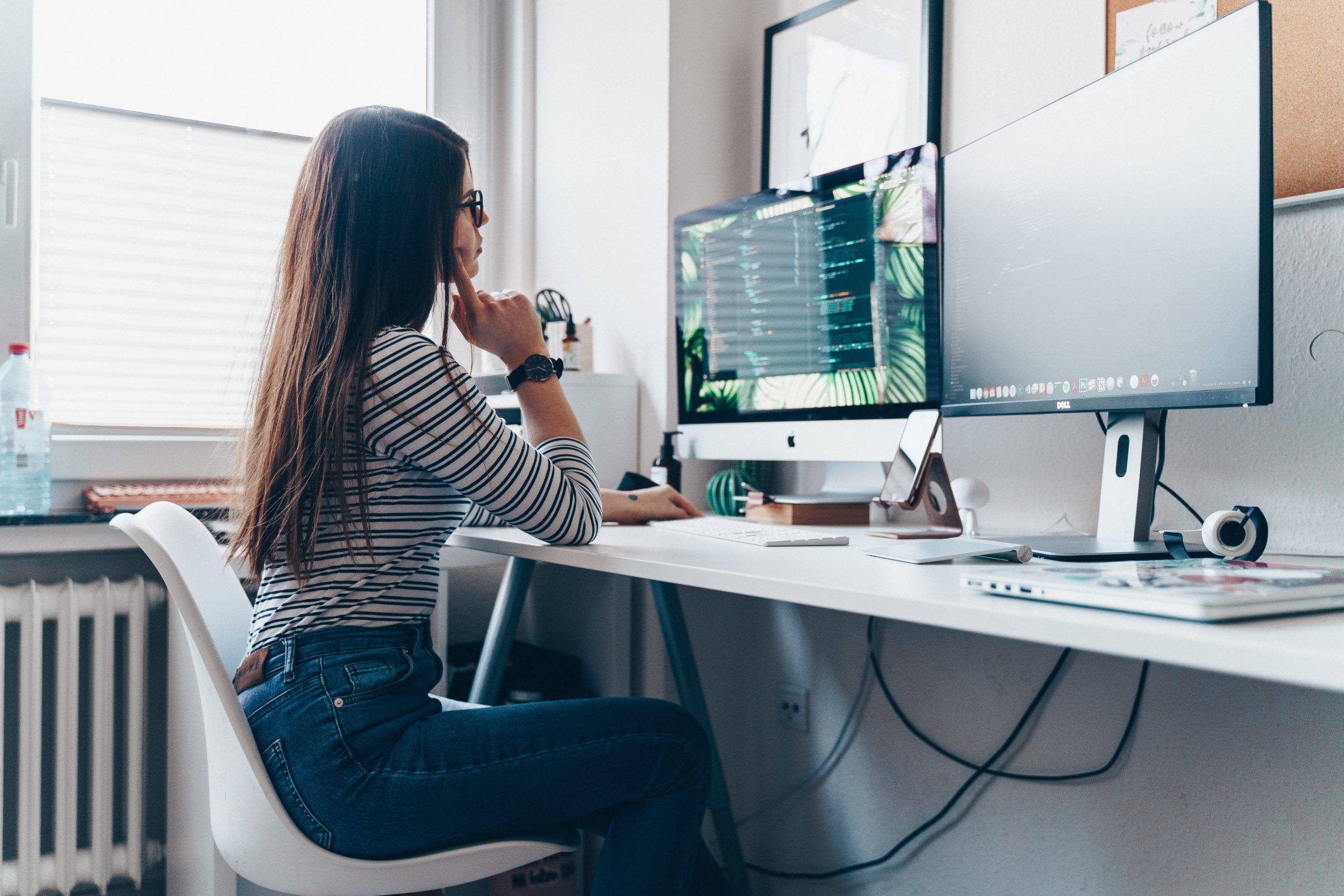 Girl with long brown hair sitting at desk looking at her monitor and being productive